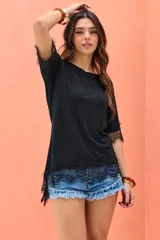 Remera negra de corte asimétrico, con mangas cortas y detalles de encaje en el dobladillo y las mangas.