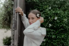 Buzo de punto color crema, con cuello polo y cierre frontal parcial con dos botones oscuros. Presenta mangas largas con puños acanalados y un diseño holgado.