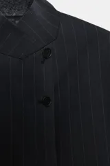 Blazer de cuello alto y manga larga con cierre frontal de botones. Presenta un diseño de raya diplomática, falsos bolsillos de vivo en el delantero y abertura en la espalda.