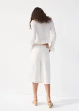 Cardigan de punto fino color blanco, con escote en V, mangas largas con puños acampanados y cierre delantero con cordones para atar.