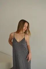 Vestido largo de jersey con estampado de lunares blancos sobre fondo negro. Presenta breteles finos, escote en V y un calce holgado y fluido.