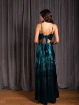 Vestido largo metalizado color negro, con tirantes finos, escote en V, falda plisada y espalda abierta con nudo.