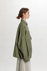 Campera bomber ligera color verde militar, confeccionada en 100% algodón, con bolsillos frontales con solapa, cierre de botones y cordón ajustable en el ruedo.