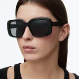 Lentes de sol con montura cuadrada oversized de color negro y lentes polarizadas oscuras. Diseño bold con cantos suavizados.