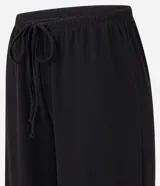 Pantalón flare negro con textura acanalada, cintura elástica con lazo y confeccionado con viscosa certificada.