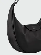Cartera hobo Longchamp modelo Le Pliage Xtra de cuero color negro, con diseño curvilíneo tipo media luna, asa ajustable con herrajes metálicos y solapa frontal con cierre de botón a presión y logo grabado.