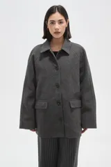 Tapado de paño color gris, con cuello camisero, cierre frontal de botones y bolsillos laterales con solapa.