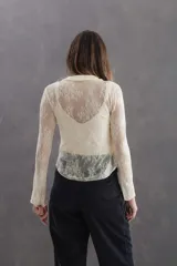 Blusa de tul bordado color manteca, con estilo romántico bohemio. Presenta cuello tipo camisa, escote en V con pechera fruncida y detalles de tiras de terciopelo en colores contrastantes. Posee mangas largas y diseño levemente elastizado.