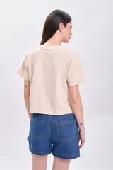 Remera color crudo de corte cropped, con mangas cortas y estampa frontal con la frase 'Rock and Roll' y un rayo alado.