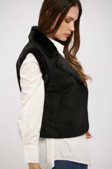 Chaleco negro de gamuza sintética con interior de piel sintética, diseño sin mangas y cierre frontal con botones.