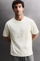 Camiseta de corte regular fit confeccionada en algodón, con cuello redondo y manga corta. Presenta un estampado frontal con el texto 'ATHLETICZ TRAINING CREW' con efecto desgastado.