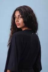 Conjunto de dos piezas (camisa y pantalón) de tejido acanalado gris, con camisa estilo kimono de manga ancha y cuello V cruzado, ajustada a la cintura con un lazo de tela.