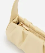 Cartera tipo baguette marca Satinato, confeccionada en PU color beige, con diseño estructurado, detalles fruncidos laterales y asa fija para el hombro.