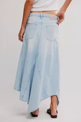 Falda larga de denim, de tiro medio y línea A, con abertura frontal, paneles con costuras y ruedo deshilachado en punta.