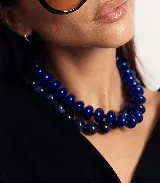 Collar de cuentas redondas y aplanadas con efecto marmolado en tonos grisáceos, con cierre metálico dorado.