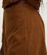 Short pollera marrón de pana con textura acanalada, bolsillos delanteros y cierre lateral con cremallera.