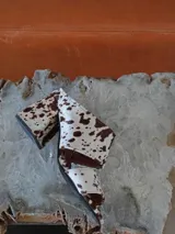 Sandalias de tacón alto y ancho, confeccionadas en piel con acabado de pelo y estampado animal print de vaca en tonos marrones y blancos, con tiras anchas en el empeine.