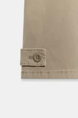Pantalón cargo de tiro medio en color beige, con cintura ajustable mediante cordones a contraste. Presenta bolsillos delanteros, bolsillos traseros con solapa y bolsillos laterales de plastrón con solapa y botones. El bajo cuenta con detalle de trabillas y botón.
