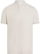 Chomba de manga corta color beige claro, confeccionada en algodón, con cuello mao y cartera de dos botones. Presenta un pequeño logo bordado en el pecho.