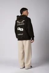 Buzo canguro oversize de algodón frizado con efecto gastado, capucha y bolsillo frontal tipo canguro. Presenta estampa gráfica sutil en el pecho.