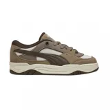 Championes urbanos Puma modelo 180, con diseño inspirado en el skate de los años 90. Presentan una combinación de tonos beige y marrón, confeccionados en una mezcla de gamuza y malla técnica. Cuentan con una suela de goma robusta en color crema y detalles de la marca en la lengüeta y laterales.