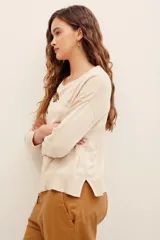 Sweater color beige de punto suave, con cuello redondo, manga larga y diseño holgado. Presenta un delicado bordado de ramas y hojas con cuentas metalizadas en la parte superior derecha del pecho y el hombro.