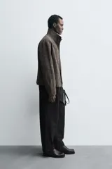 Sobrecamisa de corte relajado confeccionada en tejido con viscosa, de color gris oscuro con textura. Presenta cuello subido, cierre frontal con cremallera y bolsillos de vivo en la cadera.