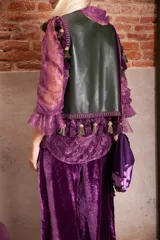 Musculosa de cuero color verde inglés, con diseño sin mangas y detalle de galón con borlas decorativas en color morado en los hombros y el ruedo.