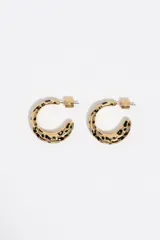 Caravanas de aro de diseño grueso en color dorado con estampado de manchas negras estilo animal print. Presentan un acabado esmaltado y cierre de perno.