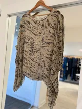 Blusa de seda italiana con estampado animal print combinando patrones de leopardo y cebra en tonos beige y marrón. Cuenta con cuello redondo y mangas amplias de caída ligera.