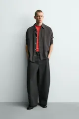 Pantalón de corte relajado confeccionado en tejido de algodón. Presenta cintura con trabillas laterales ajustables, bolsillos frontales y traseros, y un diseño distintivo de costuras laterales giradas que recorren la pernera.