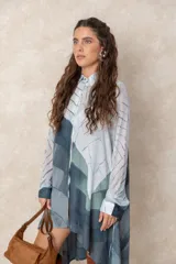Vestido tipo túnica de corte asimétrico, con diseño abotonado y mangas largas confeccionadas en microtul. Presenta un estampado abstracto en tonos azules y verdes. Versátil, puede utilizarse como vestido, túnica o camisa larga.