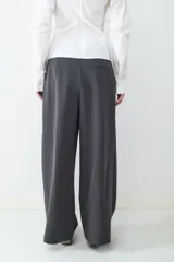 Pantalón de vestir de tiro alto con pliegues frontales, corte amplio y pernera recta. Cuenta con bolsillos laterales y cierre frontal con cremallera y botón.