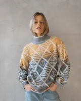 Sweater de punto con diseño geométrico en tonos gris, camel y crudo, cuello alto y mangas largas.