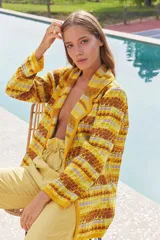 Saco largo medio con abertura frontal, bolsillos delanteros y cinto para ajustar. Presenta un diseño tejido con patrón geométrico en tonos amarillo, marrón y lila.