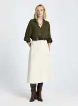 Falda midi color crudo, de tela tejida, con bolsillos delanteros, cierre frontal con cremallera y botón, y trabillas para cinturón.