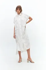 Vestido camisero midi blanco con cuello clásico, manga corta y cierre frontal con botones. Presenta volados en microtul a lo largo del frente y los hombros. Silueta cuadrada.