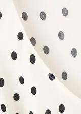 Vestido midi de viscosa fluida en color crudo con estampado de lunares negros, de corte recto, escote redondo, tirantes y bajo asimétrico.