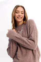 Buzo de punto de textura suave, color malva, con cuello redondo y diseño de calce relajado.