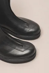 Bota corta de cuero negro con cierre frontal con cremallera y suela de goma.
