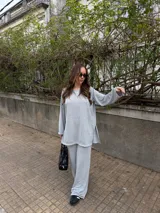 Conjunto de dos piezas de lanilla en color gris melange, compuesto por un buzo oversize de manga larga con aberturas laterales y un pantalón largo de corte recto y holgado.