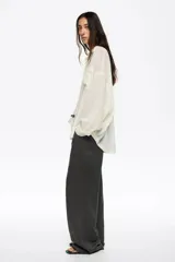 Pantalón de corte recto y tiro bajo, color crudo, con bolsillos frontales tipo alforja y cintura ajustable con cordón.