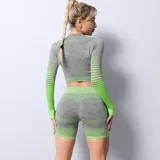 Remera deportiva de manga larga, confeccionada en tejido seamless de textura jaspeada en color gris con detalles en verde neón. Presenta un diseño ajustado al cuerpo con efecto degradado en las mangas.