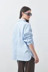 Camisa de manga larga de algodón en color blanco, con cuello clásico, cierre frontal de botones y silueta relajada.