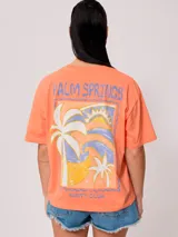 Remera color salmón de corte holgado, con estampado pequeño en el frente que incluye un arcoíris y el texto "Rusty Club".