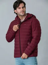 Campera acolchada Calvin Klein color bordó con capucha y cierre frontal con cremallera. Tiene bolsillos laterales con cremallera y logo de la marca en el pecho y en la manga.