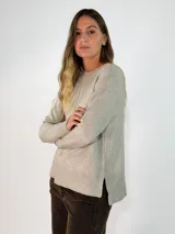 Sweater de punto color beige, con cuello redondo, manga larga y diseño con tajos laterales. Presenta un dobladillo trasero ligeramente más largo que el delantero y detalles de costura central vertical.