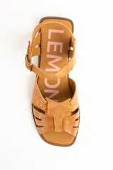 Sandalias planas de cuero color caramelo, con tiras entrelazadas en la parte delantera y tira ajustable con hebilla metálica en el tobillo.