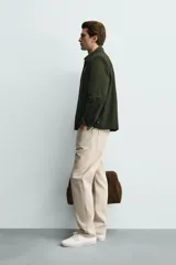 Pantalón jeans de corte recto y tiro medio, confeccionado en denim de algodón color beige con efecto lavado, bolsillos clásicos y cierre frontal con cremallera y botón.