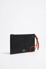 Neceser de piel vacuna color negro, con estructura blanda y cierre de cremallera. Incluye un asa de mano de cordón extraíble con detalles en naranja y blanco.